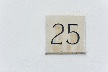 House number twent five on a stone plaque with a green wall back