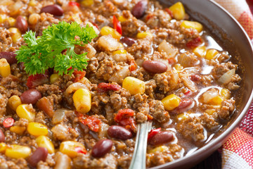 spicy Mexican dish chili con carne in a brown pottery plate
