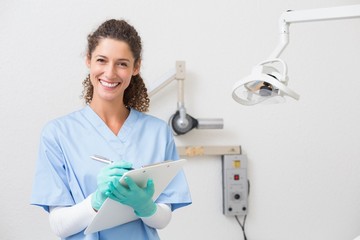 Dentist in blue scrubs writing on clipboard