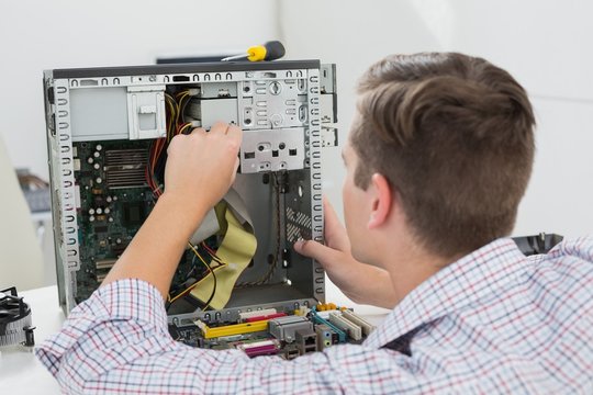 Young technician working on broken computer