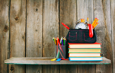 Books and school tools on a wooden shelf.