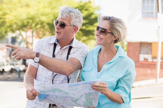 Happy tourist couple using map in the city