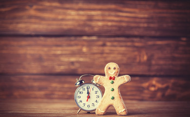 Cookie man and retro alarm clock on wooden background