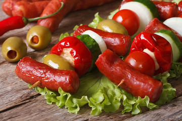 grilled sausages with tomato, olives, chili, onions on skewers