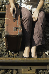 Fototapeta na wymiar Woman and vintage suitcase on railway road