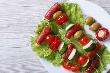 grilled sausages with vegetables on skewers closeup top view