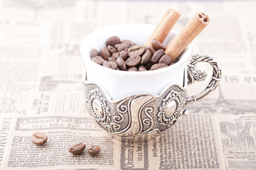 White coffee cup on newspaper with cinnamon