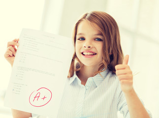 smiling little student girl with test and A grade