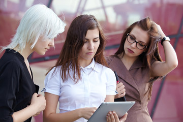a group of businesswomеn from tablets on the street