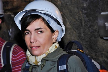 young woman inside the cave with a protective helmet