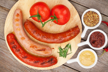 Various grilled sausages with condiments and tomatoes