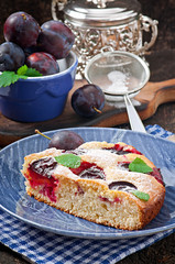 Delicious homemade cake with plums on a wooden background