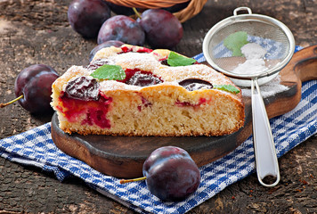 Delicious homemade cake with plums on a wooden background