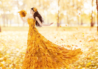 Autumn woman in fashion dress of fall maple leaves, artistic
