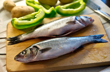 Two cleaned sea bass on a wooden board