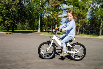 Fototapeta na wymiar Cute little girl riding fast by bicycle