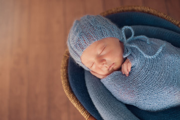 Small Sleeping Newborn Baby in Basket on Wooden Floor