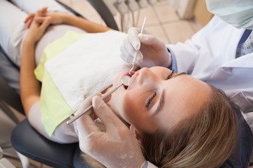 Obraz na płótnie Canvas Dentist examining a patients teeth in the dentists chair