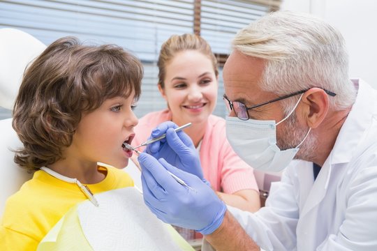 Pediatric dentist examining a boys teeth