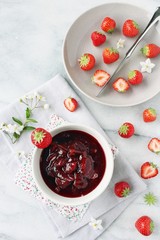 Homemade strawberry jam and strawberry on a light background.