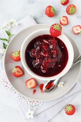 Homemade strawberry jam and strawberry on a light background.