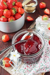 Homemade delicious strawberry jam on a rustic wooden table.