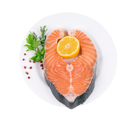 Raw salmon steak with parsley and lemon slice.