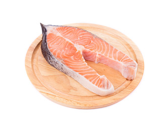 Fresh salmon steak on wooden platter.