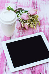 a tablet computer, a glass of coffee and  lilies of valley and t
