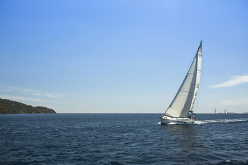 Fototapeta premium Sailing ship yachts with white sails in the open sea.