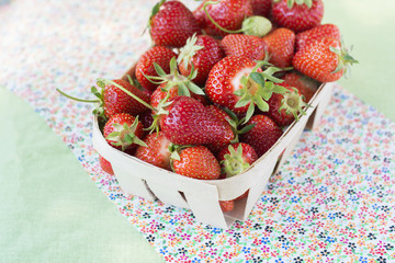 Strawberries in a wooden basket on a floral background