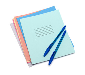 exercise books and pens on a white background