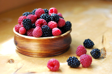 raspberries and blackberries in a wooden bowl