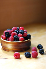 Raspberries and blackberries in a wooden bowl