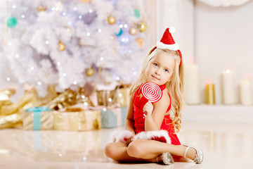Obraz na płótnie Canvas Beautiful little Santa girl near the Christmas tree. Happy girl