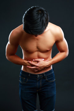 Young Man Holding His Sick Stomach In Pain On Black Background