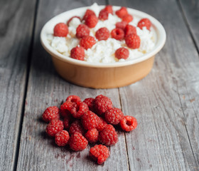 Curd with ripe raspberries on wooden background