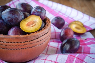 organic ripe plums in a clay bowl