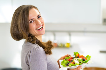 Portrait of happy young housewife with greek salad