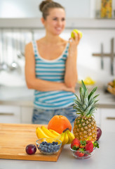 Closeup on fruits on table and woman with apple in background