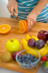 Closeup on young woman cutting orange