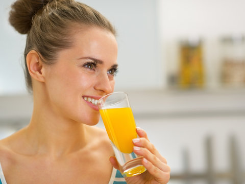 Portrait of happy young woman drinking fresh orange juice