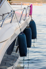Side of a yacht with three blue fenders, used to protect boat