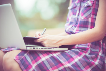 Naklejka premium Beautiful young woman using laptop in park
