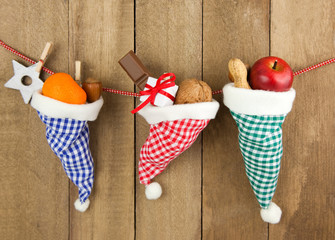 3 gefüllte Nikolausmützen vor Holz hängend