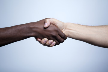 Interracial handshake on gray background