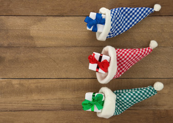 Geschenke und Weihnachtsmütze auf Holzbrett