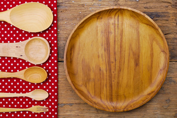 Wooden plate, tablecloth, spoon, fork on old table background