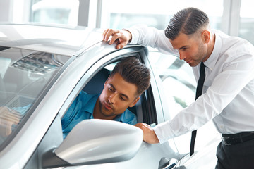 Obraz premium Car Sales Consultant Showing a New Car to a Potential Buyer in S