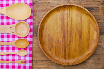 Wooden plate, tablecloth, spoon, fork on old table background